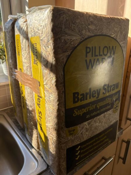Large packs of Pillow Wad barley straw bedding stacked beside a kitchen sink.